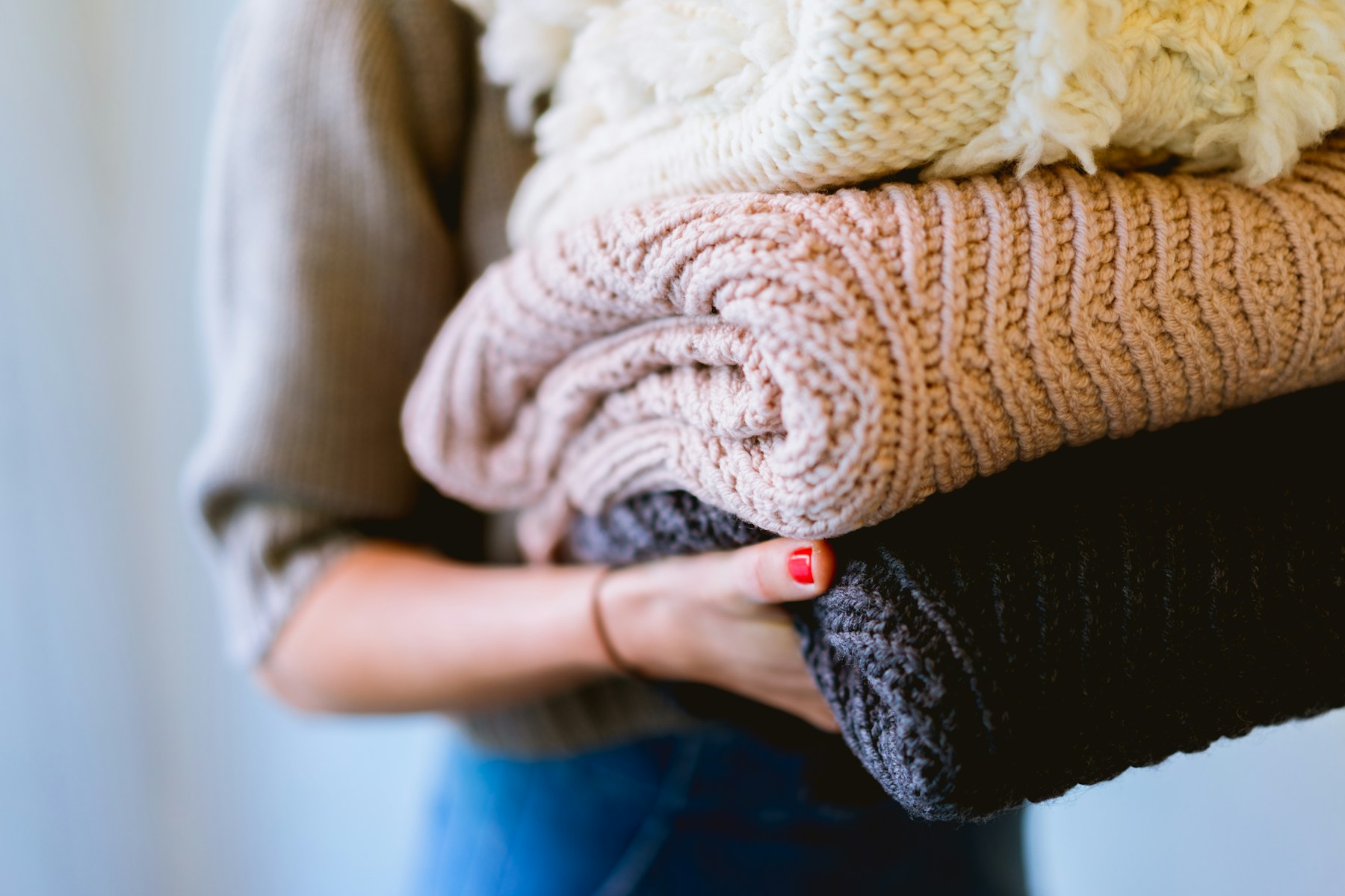 Hands holding a wool knit, one of the fabrics that needs a gentler approach to odour.