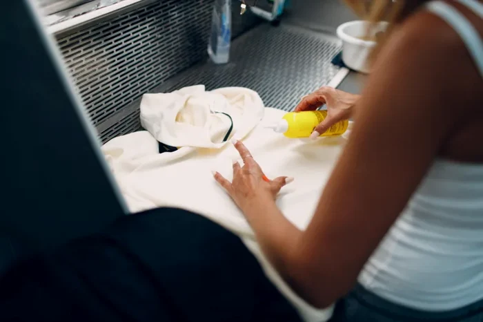 Sunscreen stain being treated on a white shirt at a laundry sink
